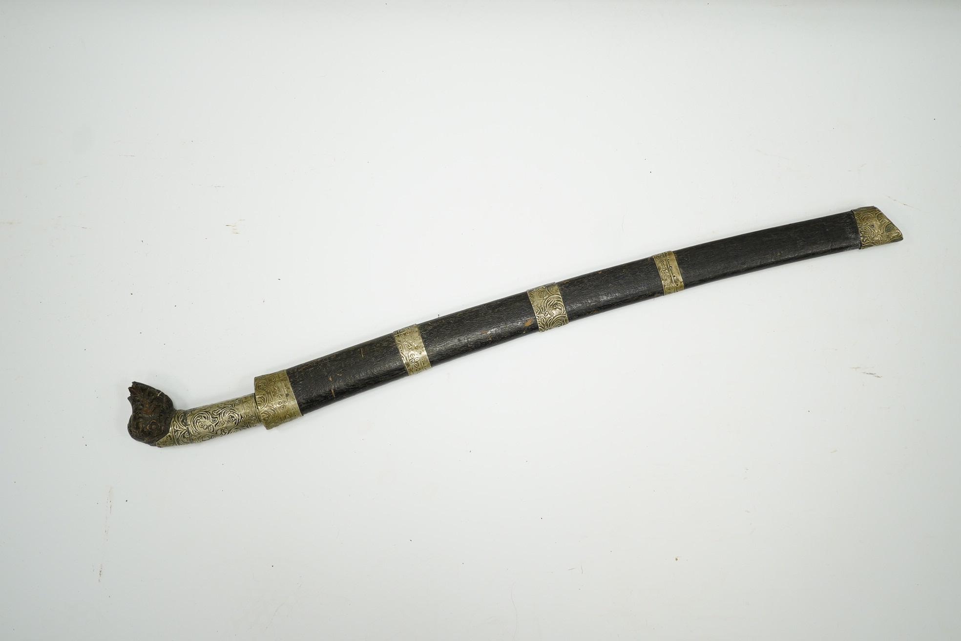 A Malaysian sword Parang, with broad curved pattern welded single edged blade, carved horn pommel, and embossed nickel mounts, in its wooden scabbard. Condition - good